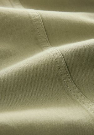 Light olive-green fabric with a smooth texture, featuring visible stitching details and subtle sheen, conveying a soft, durable appearance.