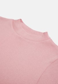 Suéter de cuello alto rosa claro con una textura suave, diseño ajustado y cuello de canalé, que muestra un estilo minimalista.