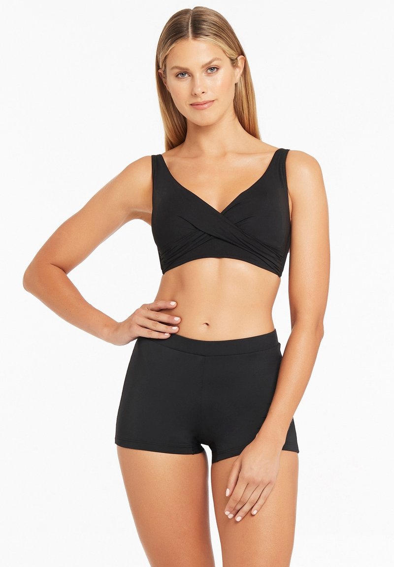 Zwart zwemtop met een crossover-design en brede bandjes, gedragen met hoge zwarte zwemshorts. Gladde textuur, minimalistische stijl.