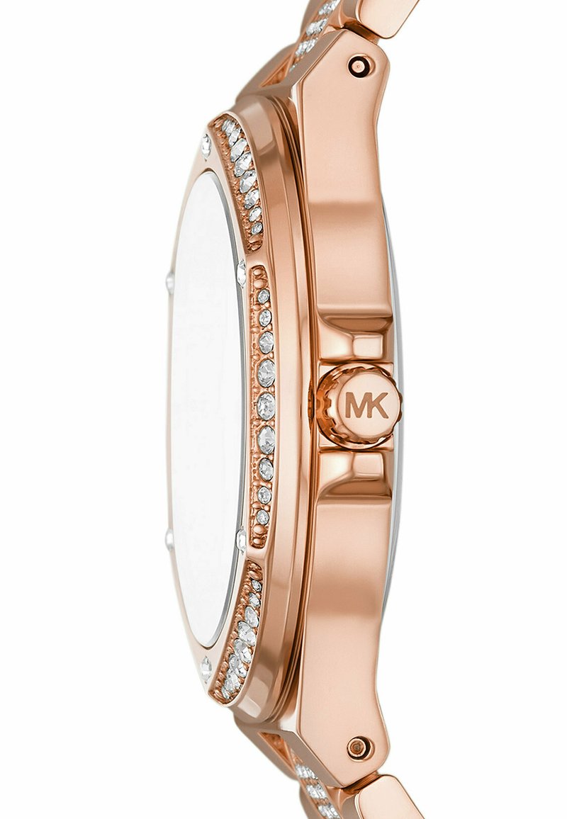 Złoty różowy zegarek z okrągłą kopertą, przezroczystą szkiełkiem, ozdobną brzegu z drobnymi kamieniami oraz solidnym metalowym paskiem z detalem logo.