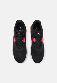 Dvojice černých atletických bot Puma s bílými podrážkami a červenými akcenty na tkaničkách, zobrazená zhora na bílém pozadí.