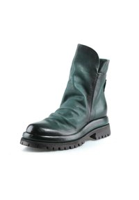 Bottine en cuir vert foncé avec une texture froissée, un bout arrondi et une semelle noire épaisse à crampons sur fond blanc.