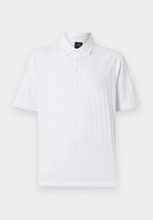 Polo de manga corta blanco con textura sutil de diamante, tres botones y una pequeña etiqueta negra de Armani Exchange en el interior del cuello.