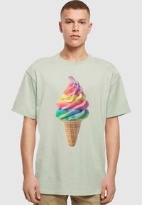 Lys grøn kortærmet T-shirt med et farverigt isvaffel grafik, der viser sv aner af pink, gul, blå og grøn på en vaffelcone.