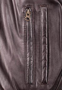 Braunes Leder-Reißverschlussetui mit strukturiertem Finish, ausgestattet mit einem bronzefarbenen Reißverschluss und einem angrenzenden flachen Lederpanel.