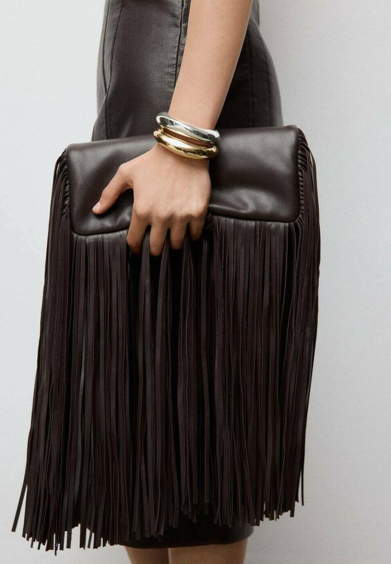 Tamno smeđi kožnati neseser s dugačkim resama, pravokutnog oblika i glatke teksture. Metalne narukvice ukrašavaju ruku koja drži torbu.