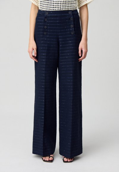 Pantalons larges navy à rayures verticales, avec un tissu texturé, taille haute et accents de double bouton sur les poches avant.