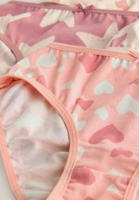 Zwei Paar Baumwollunterhosen in sanften Pastellfarben; eine mit rosa und weißen Herzen, die andere in Rosatönen mit abstrakten Formen.