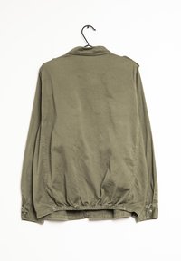 Veste vert olive en coton, avec un col, des poignets à boutons, une taille élastiquée et des détails sur les coutures latérales. Texture douce.