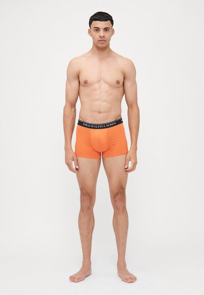 Oranžové trenýrky vyrobené z jemné látky s černým páskem, na kterém je logo značky "POLO RALPH LAUREN." Přiléhavý střih a délka do poloviny stehna.