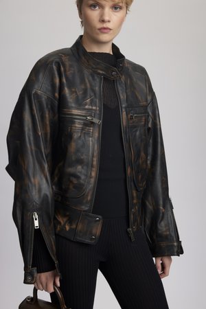 Sort og brun marmorert læderjakke med høj krave, flere lynlåse og oversize ærmer. Bæres over en sort ribbet top.