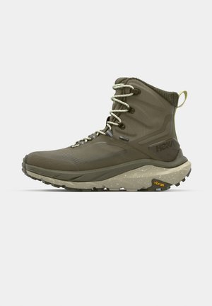 Olivgrön vandringskänga med texturerad tyg, förstärkt tå, vadderad krage och Vibram-gummisula, med ljusa snören och detaljer.