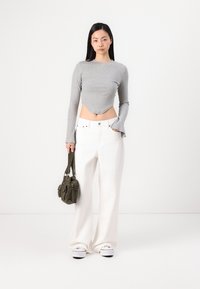 Hallitusjänkret pikematel varrukatel crop top, valged laiad püksid ja oliivroheline taskutega kuryu-kott. Välja näeb valged sneakers.