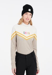 Langärmliges Skitop in Beige mit gelben Chevronstreifen und pinkfarbener Grafik. Verfügt über einen hohen Kragen und einen leichten, dehnbaren Stoff.