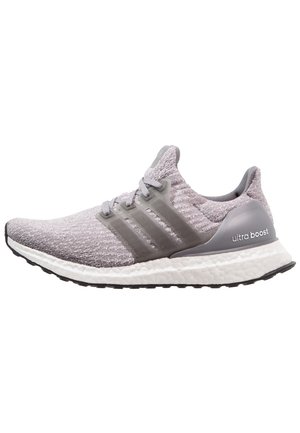 Jasnoszary but do biegania Adidas Ultra Boost z dzianinową cholewką, przezroczystą powłoką, białą amortyzowaną podeszwą środkową i czarną, ryflowaną podeszwą zewnętrzną.