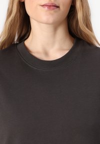 Donkergrijze pullover sweatshirt met een geribde kraag en zachte textuur, met een minimalistisch ontwerp en geen zichtbare patronen of accenten.