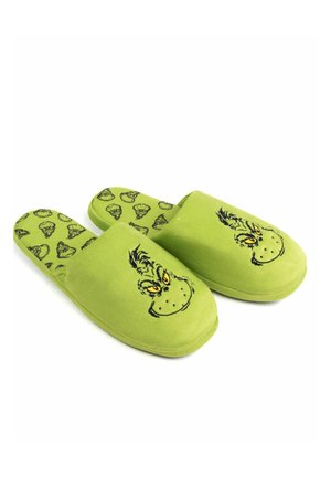 Grüne Hausschuhe mit weicher Textur, die vorne ein Grinch-Gesicht und auf der Innensohle ein wiederholtes Grinch-Muster zeigen.