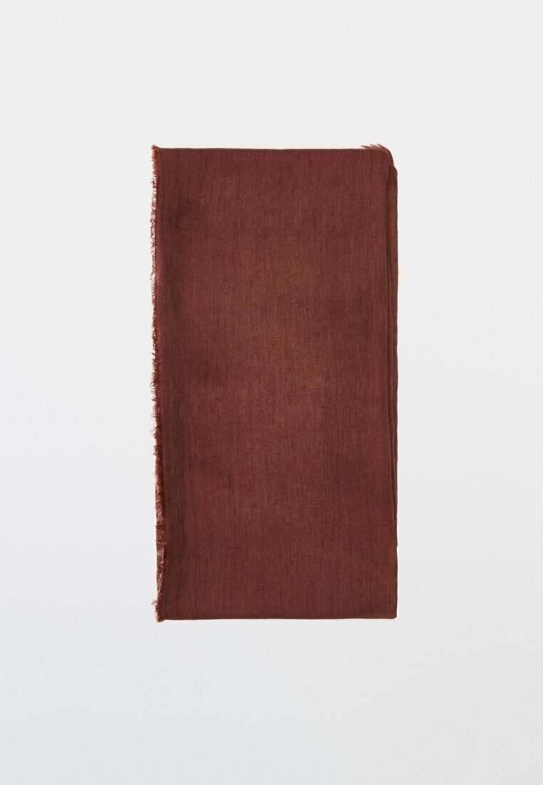 Tissu brun rectangulaire plié avec un bord légèrement effiloché d'un côté, posé sur un fond clair uni.