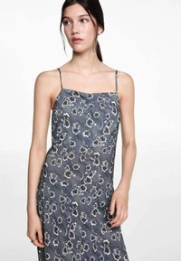 Blommig glidsärk i mörkgrått med tunna band, med vita och ljusgrå blommönster. Lättviktig tyg med en slät textur.