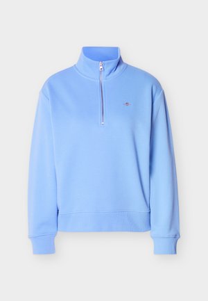 Light blue quarter-zip sweatshirt with high collar, long sleeves, ribbed cuffs and hem, and a small embroidered logo on the chest.