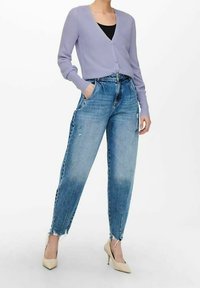 Ljuslila ribbad cardigan med v-ringning och knappstängning, tillsammans med slitna blå högmidjade jeans och beige klackskor.