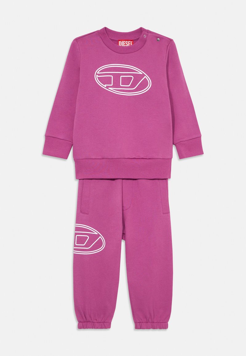 Violet kreklu un bikses komplekts no mīksta auduma. Krekla priekšpusē ir balts logo un pogu detaļa; biksēm ir elastīgas padeves un sānu kabatas.