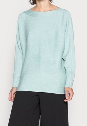 Maglione largo color teal chiaro con scollo ampio, texture a coste e maniche lunghe, abbinato a pantaloni neri a gamba larga.