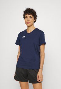 T-shirt en coton bleu marine avec un décolleté en V et des manches courtes. Présente le logo Adidas blanc sur le côté supérieur gauche. Design simple et uni.