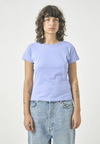 Kurze Ärmel, lila Baumwoll-T-Shirt mit Rundhalsausschnitt und lässiger Passform, kombiniert mit hellblauen Jeans.