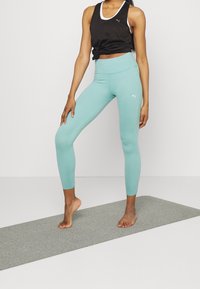 Svart sportig linne med vita detaljer och ljusblå högmidjade leggings, slät textur, figurnära design, inga synliga mönster eller logotyper.