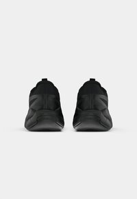 Čierne atletické topánky so štíhlym dizajnom, mäkkým textilným zvrškom, textúrovanými akcentmi a hrubou gumovou podrážkou, na ktorej je logo Reebok.