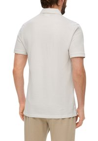Helles graues Poloshirt aus weicher Baumwolle, mit klassischem Kragen und kurzen Ärmeln, geradem Saum und seitlichen Schlitzen für mehr Bewegungsfreiheit.