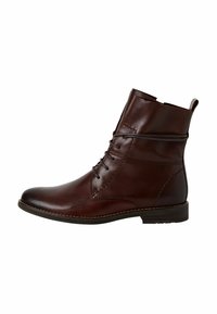 Bottine en cuir marron avec un devant lacé, un bout arrondi et des détails cousus. Elle dispose d'un petit talon et d'une languette à l'arrière.