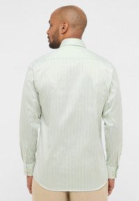 Camicia da uomo a maniche lunghe con colletto, caratterizzata da righe verticali alternate in verde chiaro e bianco, realizzata in tessuto liscio con polsini abbottonati.