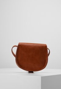 Bolso bandolera de imitación cuero marrón con forma redondeada, detalles de costura y dos asas laterales. Textura lisa, diseño simple.