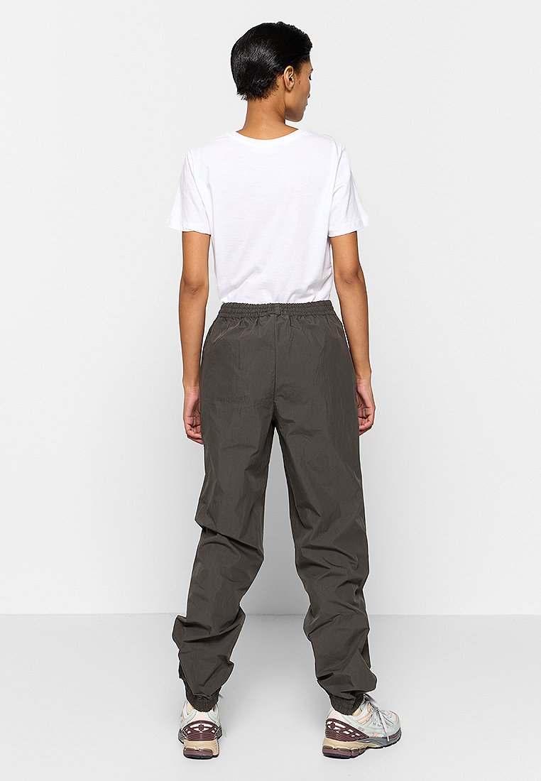 Dunkelgrüne, leichte Hose mit elastischem Bund, entspannter Passform und elastischen Bündchen, kombiniert mit einem schlichten weißen T-Shirt.