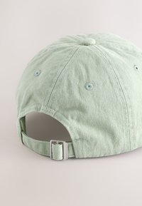 Cappellino da baseball in cotone verde chiaro con finitura testurizzata, fibbia metallica regolabile e fori di ventilazione cuciti sulla corona.