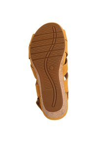 Sandalia amarilla con una suela de goma texturizada, plantilla de corcho y múltiples diseños de correas. La suela presenta un patrón de olas para mayor tracción.