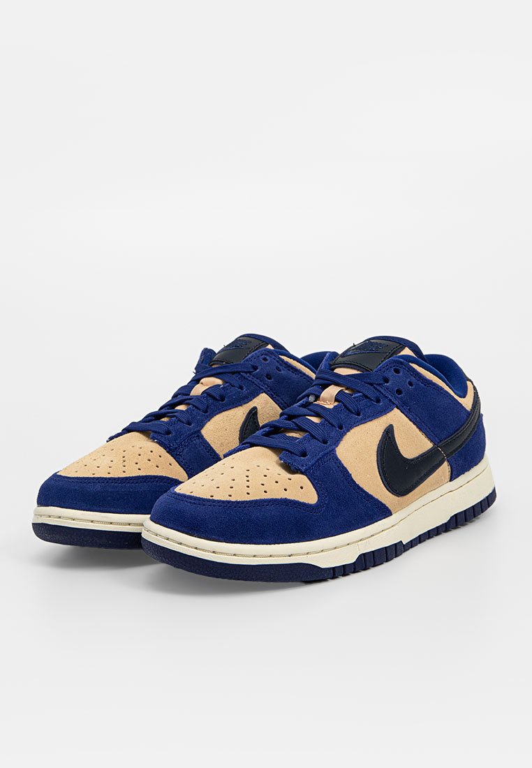 Zapatillas Nike con parte superior de ante azul y acentos en color beige, puntera perforada y logo de swoosh negro; plantilla blanca y suela texturizada negra.