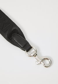Sort stofrem med tekstureret design, læder detaljer og en sølvmetal lobster clasp med gravéreret branding.