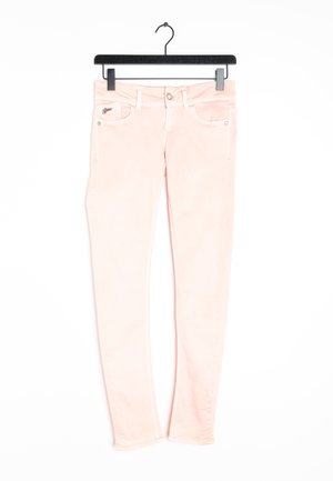 Lichtroze slim-fit spijkerbroek hangend aan een zwart hangertje, met voorzakken, riemlussen en een knoopsluiting.
