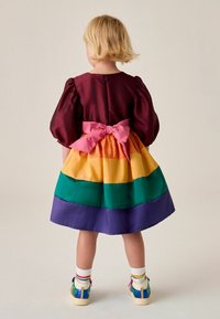 Farbenfrohes Satin-Kleid mit Puffärmeln und einer pinken Schleife in der Taille, mit horizontalen Streifen in Lila, Grün, Gelb und Orange.