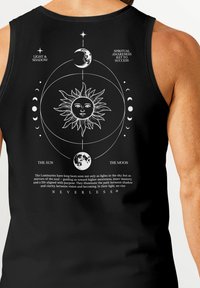 Schwarzes Tanktop mit weißen himmlischen Grafiken, darunter eine Sonne, ein Mond und Text. Das Material wirkt glatt und hat eine figurbetonte Passform.