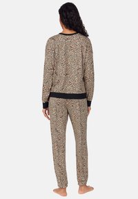 Conjunto de pijamas con estampado de leopardo en tonos beige y negro. Parte superior de manga larga y pantalones a juego con cinturilla y puños negros, fabricados en un tejido suave y texturizado.