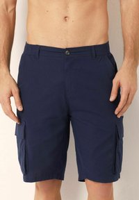 Shorts cargo de culoare bleu marin, confecționați dintr-un material moale, cu închidere pe buton, având buzunare laterale și o croială lejeră, cu o lungime până la genunchi.