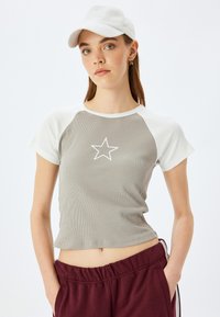 Grå ribbet t-shirt med korte ærmer og hvide raglan ærmer samt et centralt hvidt stjernes grafik, parret med bordeaux bukser med elastisk talje.