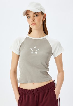 Grijze geribde t-shirt met korte mouwen en witte raglanmouwen, voorzien van een centrale witte sterafbeelding, gecombineerd met bordeauxrode elastische broek.
