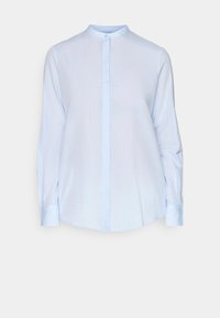 Chemise bleu clair à manches longues avec col mao, fermeture à boutons sur le devant et ourlet légèrement arrondi. Confectionnée dans un tissu lisse et léger.
