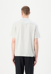 Īsām piedurknēm krekls, gaiši zaļš un balts vertikāls svītrojums, brīva piegriezuma, apkakle, mīksta auduma, noapaļots apakšmalas, redzami šuvju punkti.