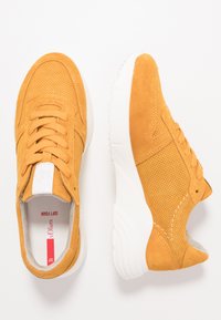 Yellow suede sneakers with perforated design, white rubber sole, lace-up closure, and contrasting soft foam interior. Includes logo tag.